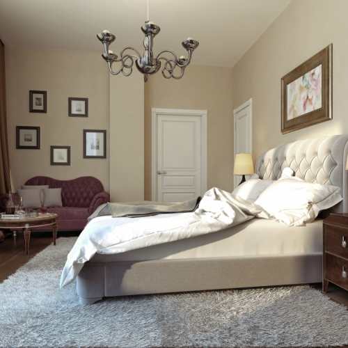 A spacious bedroom with a large bed, a plush armchair, and a chandelier