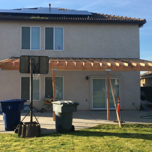 A house with a flat-roofed patio covered by a brown awning
