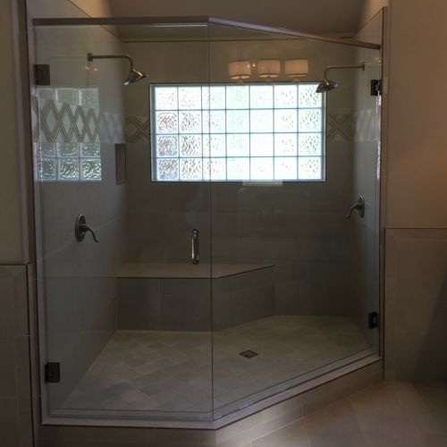 A walk-in neo-angle shower enclosure with glass doors and a built-in bench