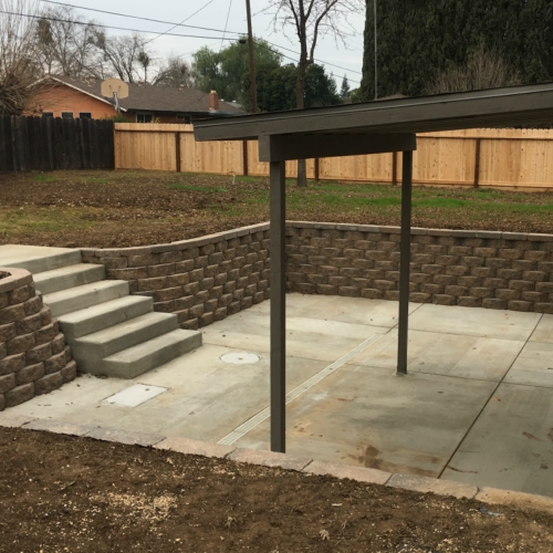 Workers pouring and smoothing wet concrete for a new patio in a backyard