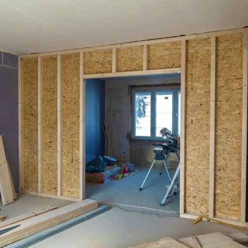 A room under renovation with one wall framed and sheathed with plywood