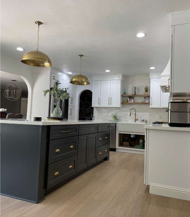 A kitchen with white cabinets, a large island with a granite countertop, and stainless steel appliances